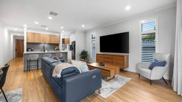 A modern living room with a sofa, a coffee table, and a TV.