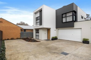 Ein modernes, zweistöckiges Haus mit Garage, Backsteinmauer und einem kleinen Garten.