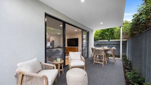 A modern outdoor patio with seating, a television, and a view of the interior. - The Torrens A Contemporary Escape in the Foothills (Kingswood)