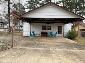 A single-story house with a covered porch, a small table, and two chairs.