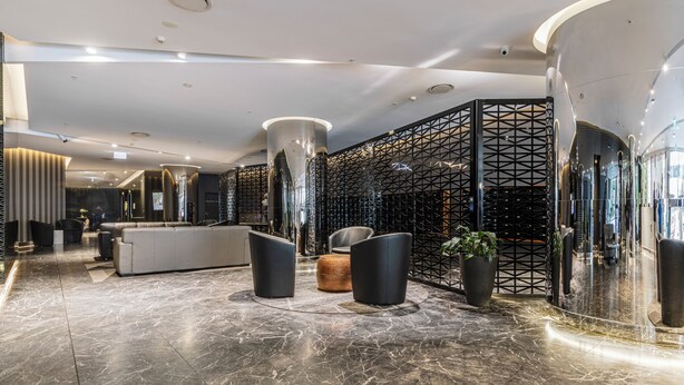 A lobby with a reception desk, seating area, and a decorative wall with a geometric pattern. - Marco Panoramic Skyline Escape with Pool and Gym (Southbank)