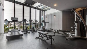 A gym with various exercise equipment, large windows, and a view of the city. - Marco Panoramic Skyline Escape with Pool and Gym (Southbank)