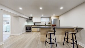 A modern kitchen with a central island, stainless steel appliances, and a wooden floor. - Spacious & Quiet Lower Unit. Mins to Airport/ HWY. 2 Parking Spots. Renovated. (Toronto)