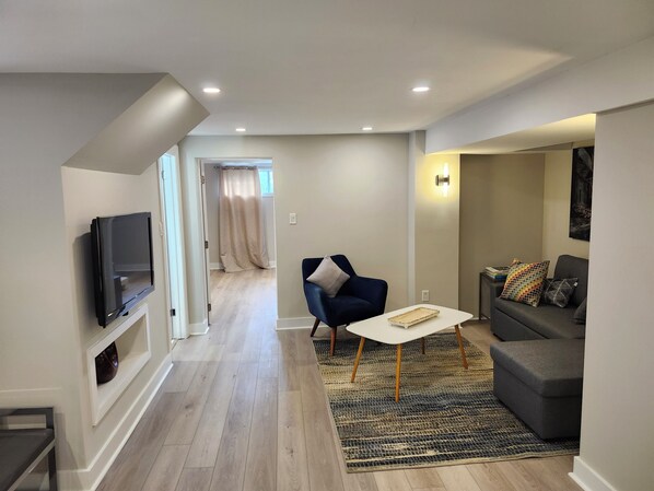 A modern living room with a flat-screen TV, a sofa, a coffee table, and a patterned rug. - Spacious & Quiet Lower Unit. Mins to Airport/ HWY. 2 Parking Spots. Renovated. (Toronto)
