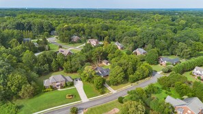 An aerial view of a residential area with houses, roads, and surrounding greenery. - Cozy 3BR Charlotte Home ~ Backyard Fire Pit (Charlotte)