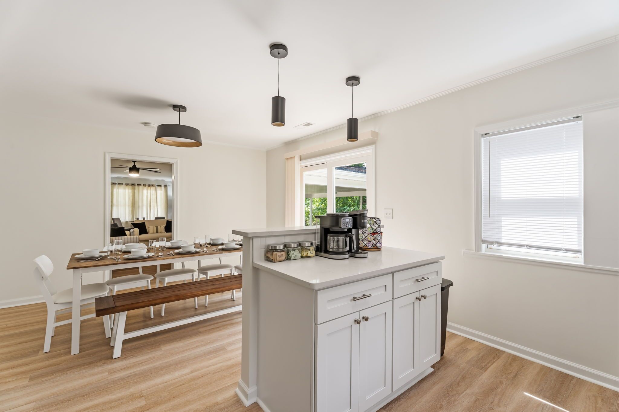Una cocina moderna con comedor, muebles blancos y un ventanal grande.