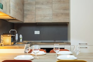 Una cocina moderna con armarios de madera, horno empotrado y comedor con una mesa dispuesta para dos.