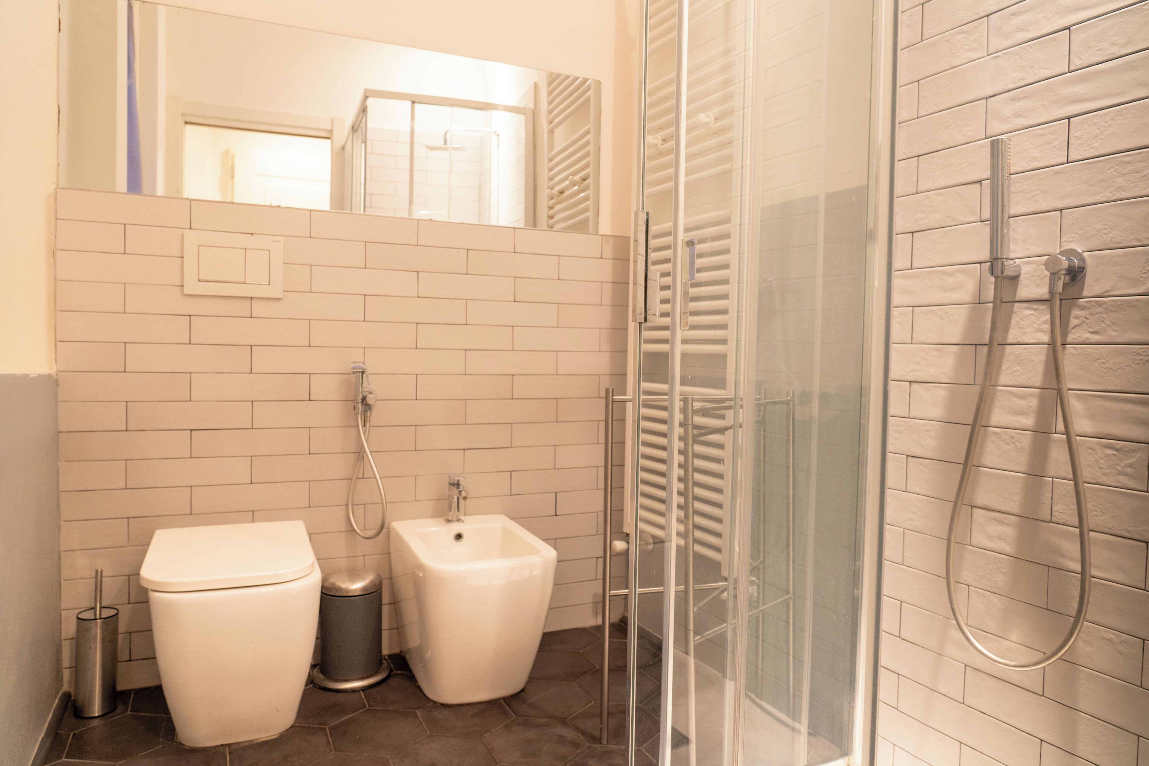 Un baño con inodoro, bidé y zona de ducha con mampara de vidrio.