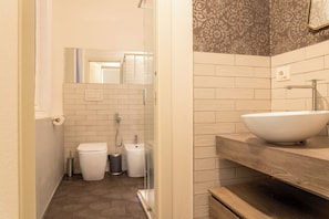 Un baño con un lavabo blanco, un espejo y una ducha.