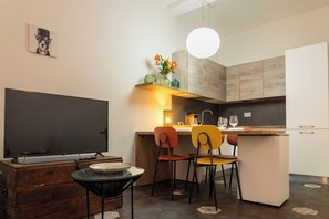 Una cocina compacta con comedor, televisor y una pequeña mesa con sillas.