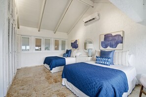 A bedroom with two beds, a white dresser, a mirror, and artwork on the walls.