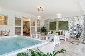 A spa area with a hot tub, white furniture, and a hanging chair.