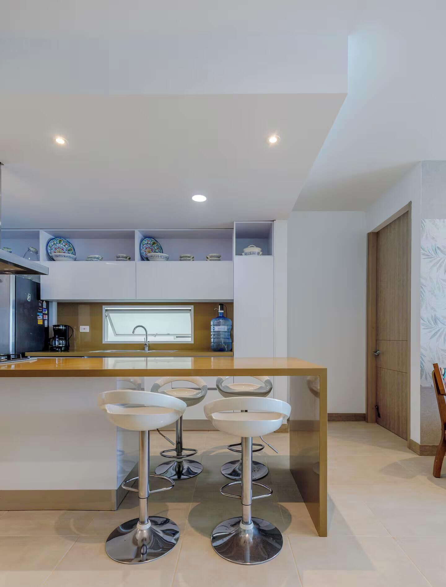 Uma cozinha moderna com uma ilha central, banquetas e uma máquina de café.