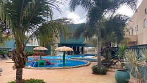 A pool area with a water slide, palm trees, and lounge chairs.