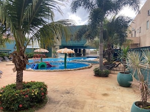 A pool area with a water slide, palm trees, and lounge chairs.