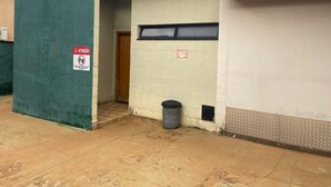 A building with a green door, a window, and a trash bin.