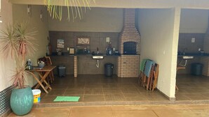 An outdoor kitchen area with a brick oven, a sink, and a dining table.