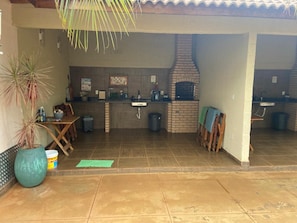 An outdoor kitchen area with a brick oven, a sink, and a dining table.