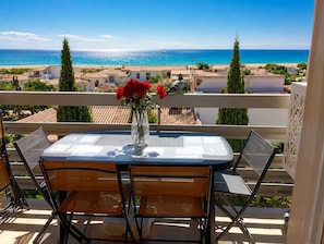 A balcony with a table and chairs, overlooking a beach and the sea. - Plaisance, quiet apartment with a view of the sea (Port-Leucate)