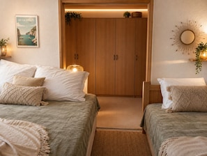 A bedroom with two beds, a wooden wardrobe, a framed picture, and a wall-mounted mirror. - Plaisance, quiet apartment with a view of the sea (Port-Leucate)