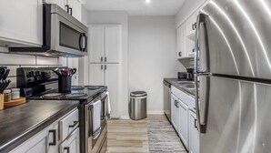 A modern kitchen with stainless steel appliances, white cabinetry, and a black countertop. - Arlington 2BR | AT&T, Globe Life, 6 Flags, Parking (Arlington)