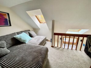 Ein Zimmer mit einer Couch, einem kleinen Tisch und Blick durch ein Fenster.