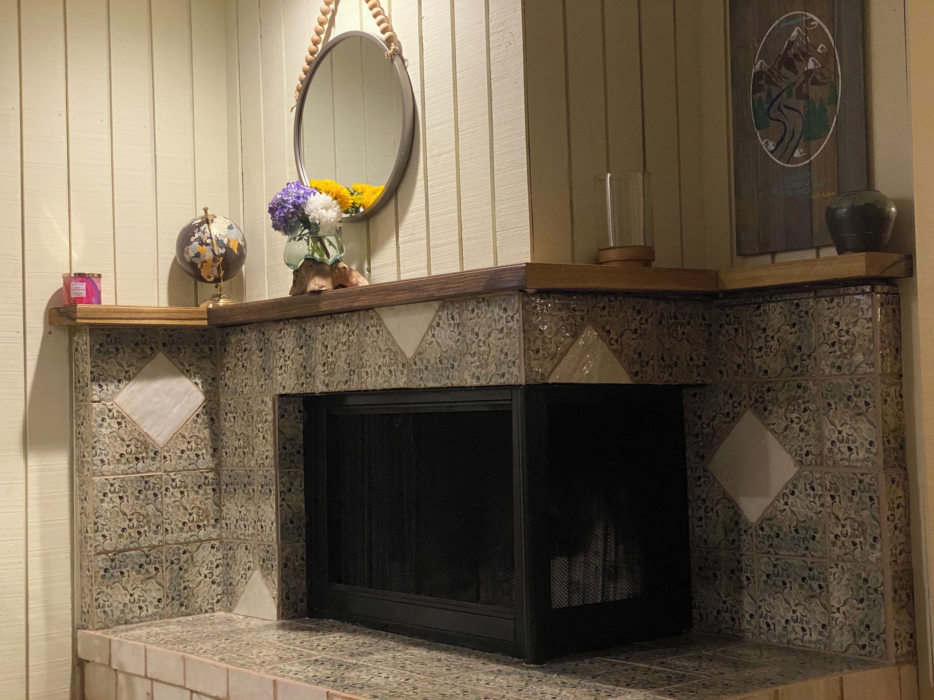 A fireplace with a decorative mantle, a mirror, and a wall-mounted artwork.