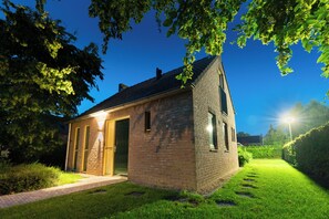A brick building with a sloped roof, a gated entrance, and a well-maintained lawn.