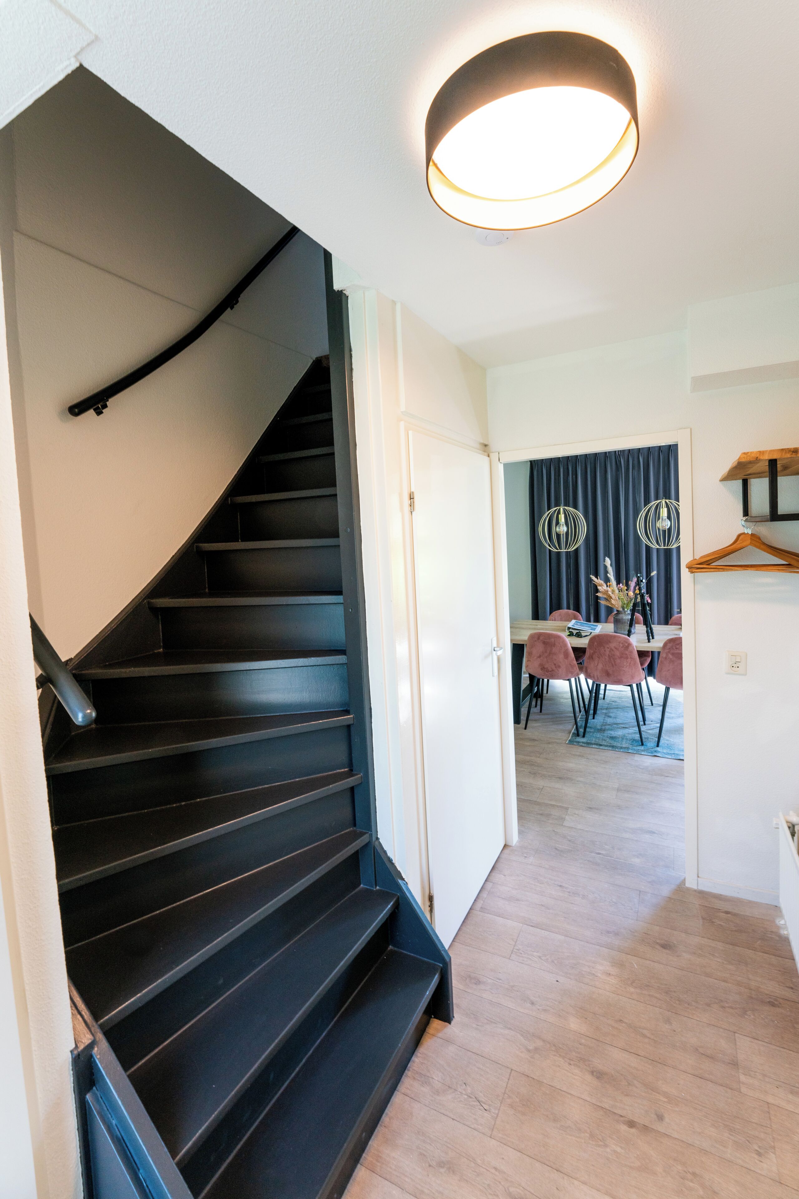 Un escalier menant à une salle à manger équipée d’une table et de chaises.