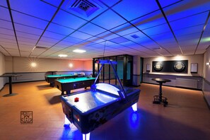 A billiards room with a pool table, two other pool tables, and a dartboard.