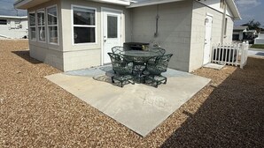 A small building with a patio area, a table with chairs, and a white fence. - Relaxing Gulf Coast Retreat in Holiday, FL – Near Beaches, Dining & Florida Adventures (Holiday)