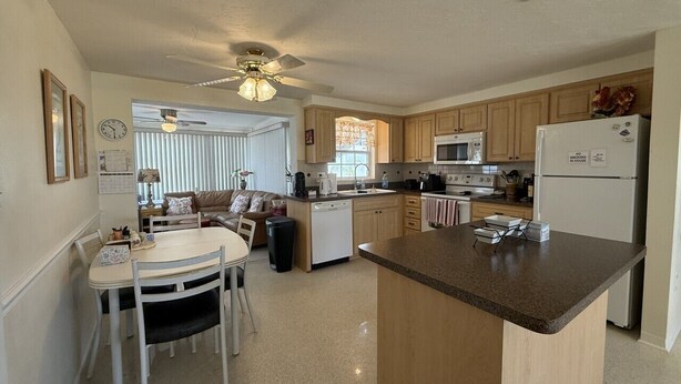 A kitchen with a central island, wooden cabinets, a microwave, and a refrigerator. - Relaxing Gulf Coast Retreat in Holiday, FL – Near Beaches, Dining & Florida Adventures (Holiday)