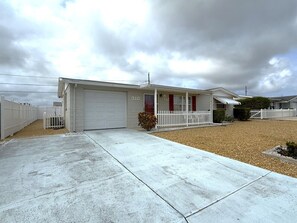 Ein einstöckiges Haus mit Garage, Veranda und Auffahrt.