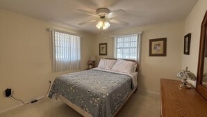 A bedroom with a bed, a ceiling fan, a dresser, and a nightstand. - Relaxing Gulf Coast Retreat in Holiday, FL – Near Beaches, Dining & Florida Adventures (Holiday)