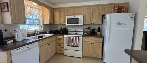 A kitchen with wooden cabinets, a white stove, a microwave, and a refrigerator.