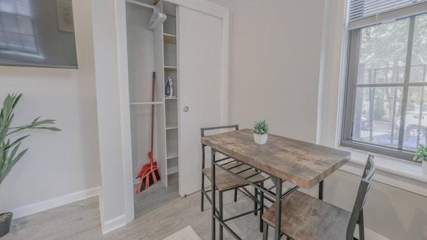 Een eethoek met een houten tafel en stoelen, een potplant en een kast met een dweil.