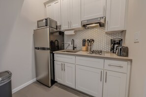 A compact kitchen with white cabinets, a stainless steel refrigerator, a microwave, a coffee maker, and a toaster. - Back Bay Area Elegant Studio Apt (Boston)
