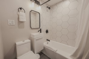 A bathroom with a toilet, sink, and bathtub. - Back Bay Area Elegant Studio Apt (Boston)