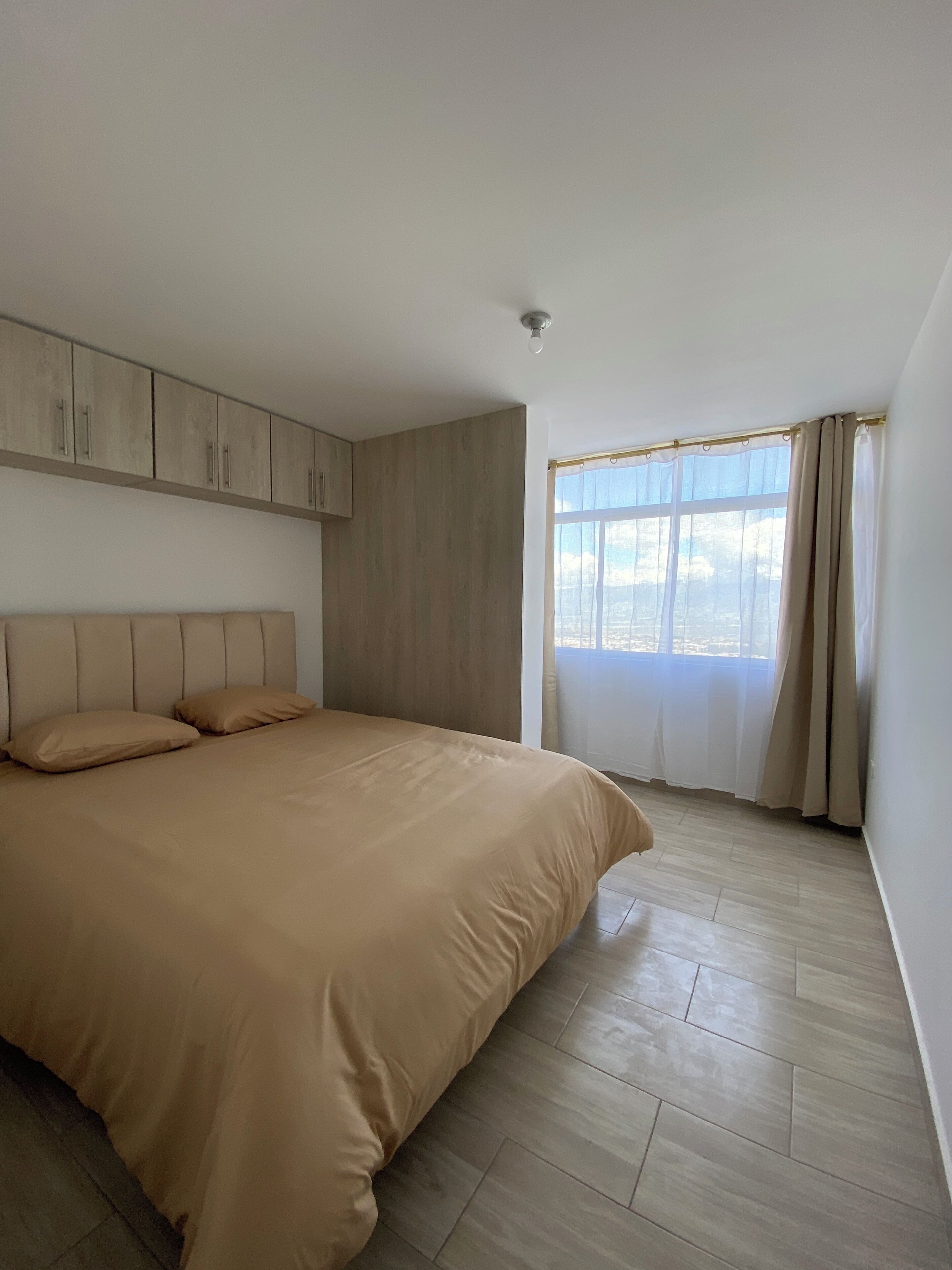 Une chambre à coucher avec un lit, une armoire et une fenêtre avec des rideaux.