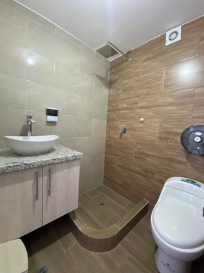 Ein Badezimmer mit weißem Waschbecken, Toilette und Duschbereich.