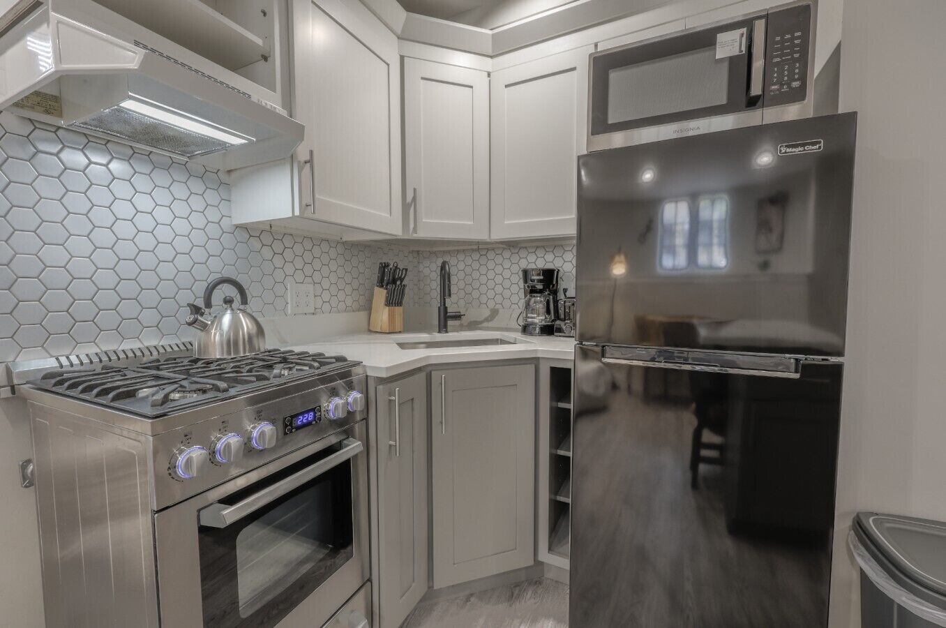 A modern kitchen with stainless steel appliances, including a stove, oven, and refrigerator, and a microwave above the counter.