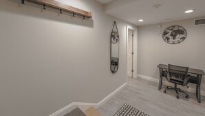 A room with a desk, chair, and a world map clock on the wall. - Spacious & Modern 1 Bedroom | Back Bay (Boston)