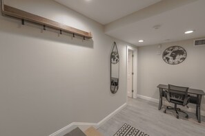 Ein Zimmer mit Schreibtisch, Stuhl und einer Wanduhr mit Weltkarten-Motiv.