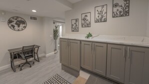 A modern kitchen with grey cabinets, a white countertop, and a dining area with a table and chairs. - Spacious & Modern 1 Bedroom | Back Bay (Boston)