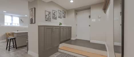A modern kitchen with grey cabinets, a white countertop, and a small stool.