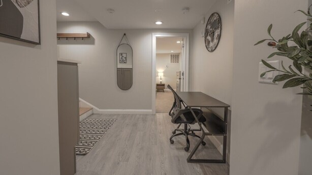 A hallway leading to a dining area with a table and chairs, a hanging artwork, and a plant. - Spacious & Modern 1 Bedroom | Back Bay (Boston)