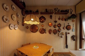 Ein Essbereich mit einem Holztisch und Stühlen, umgeben von einer Wand mit verschiedenen Küchenutensilien und Tellern.