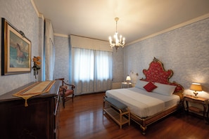 A hotel room with a large bed, a desk, a chair, a chandelier, and a window with curtains. - A cozy and elegant apartment just a short walk from downtown. Ideal for couples (Alessandria)
