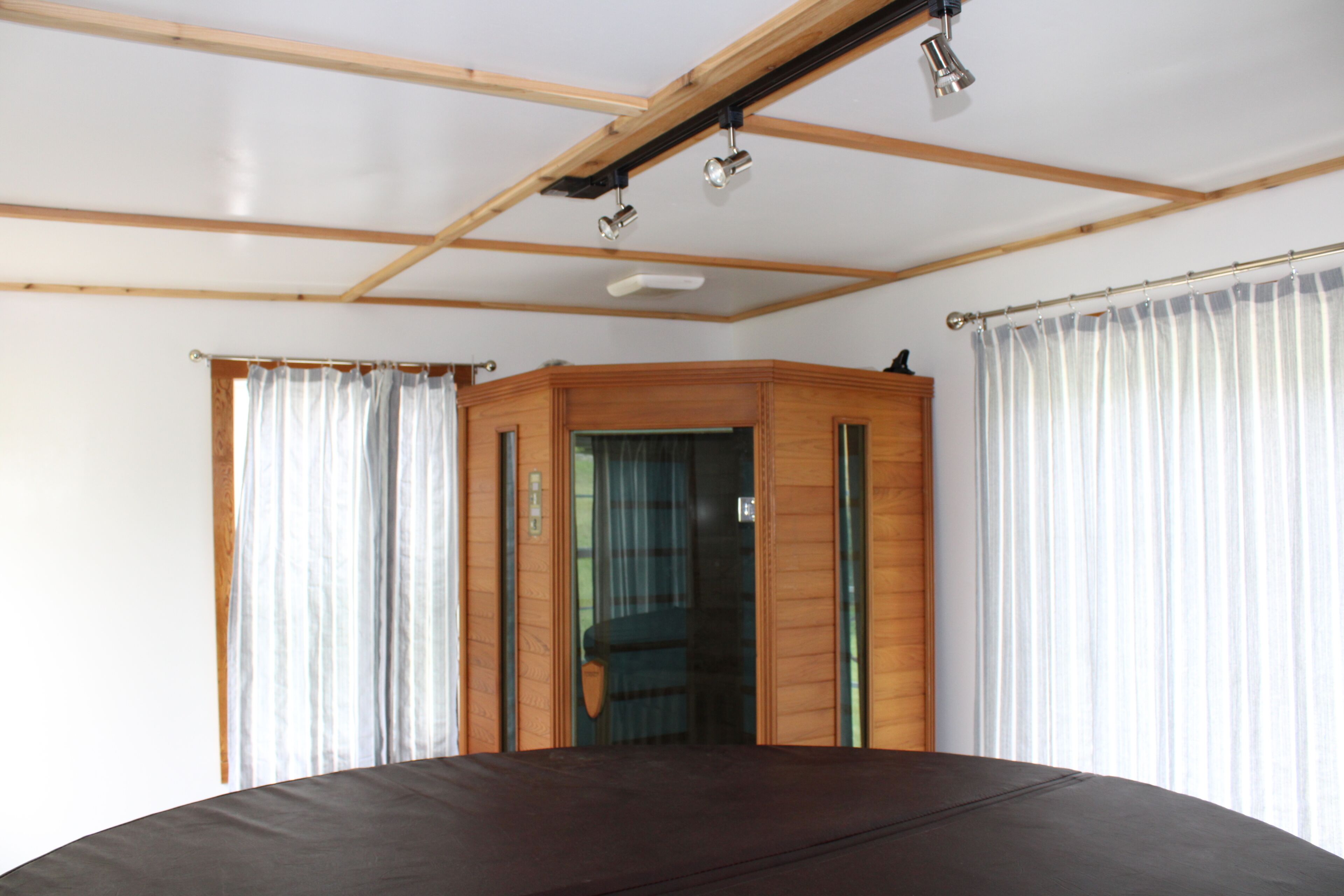 Ein Zimmer mit einem Bett, einem Holzschrank und einem Vorhangfenster.