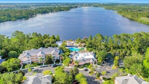 Ett hotell med en swimmingpool, omgivet av frodig grönska och en stor sjö.